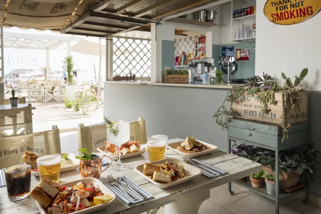 Tavolo in un ristorante con piatti di cibo e bevande, ambiente accogliente e decorazioni rustiche.