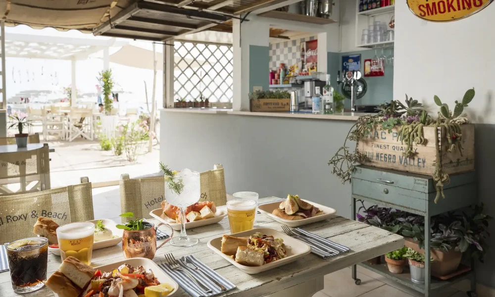 Tavolo apparecchiato con cibo e drink in un accogliente ristorante interno.
